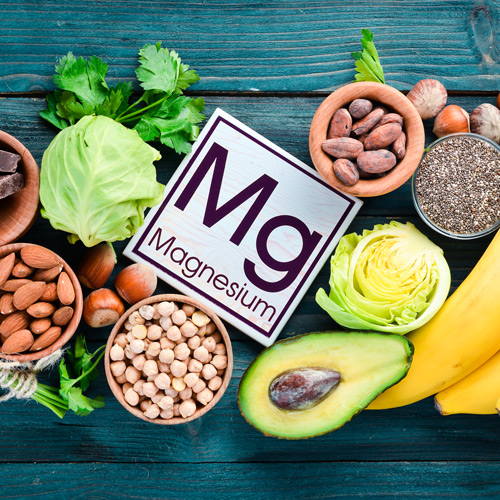 Foods containing natural magnesium. Mg: Chocolate, banana, cocoa, nuts, avocados, broccoli, almonds. Top view. On a blue wooden background.